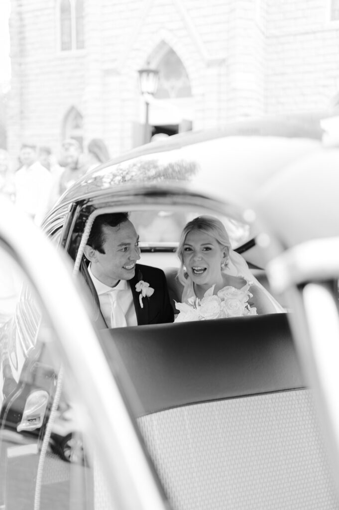 bride and groom in the get away car after their church ceremony